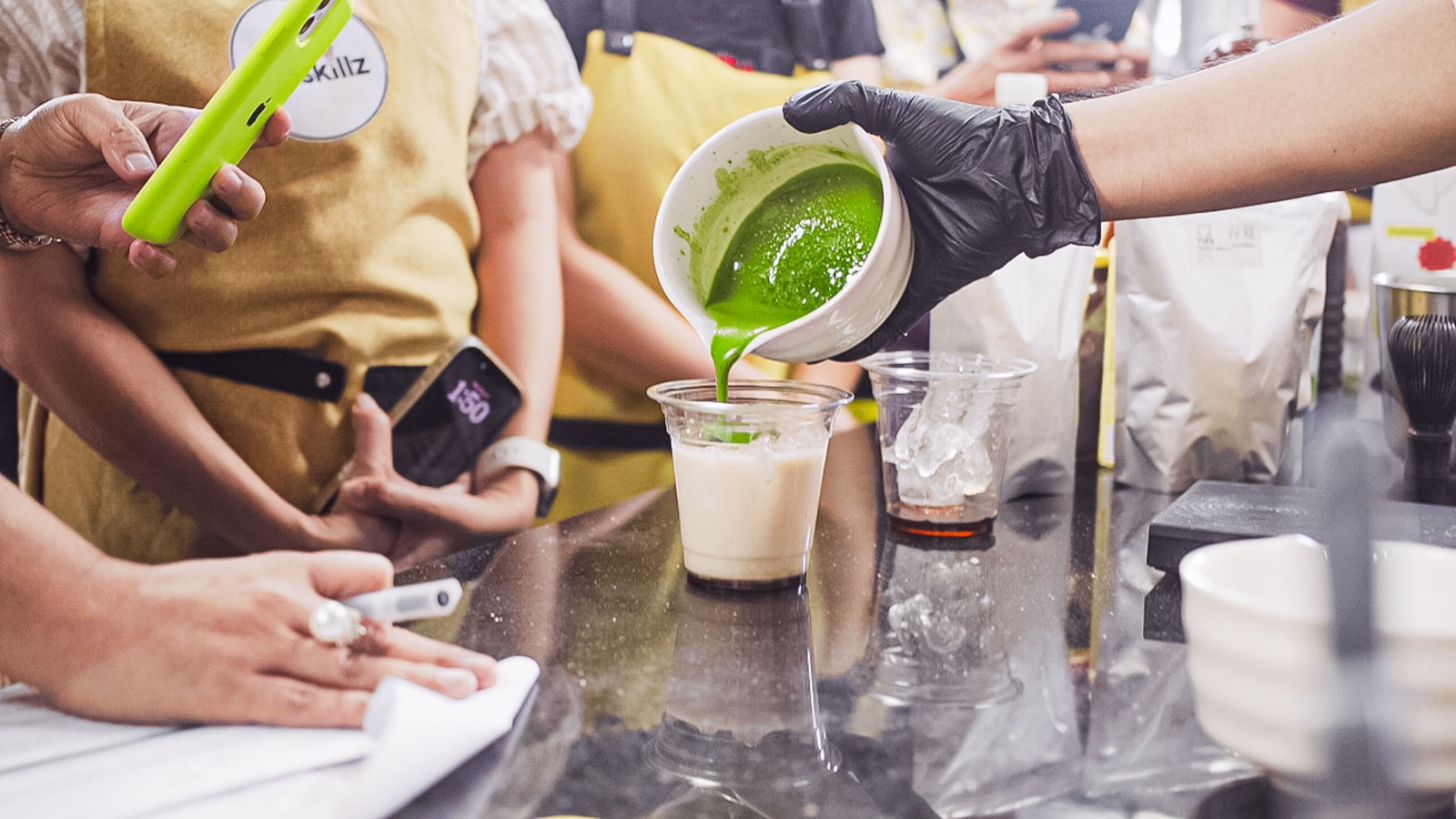 Matcha being poured over milk in a clear cup